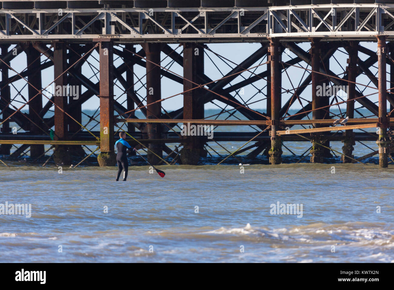 Ein Paddel boarder Paddle Boarding geht in der Nähe der Pier von Hastings einen genaueren Blick, East Sussex zu nehmen Stockfoto