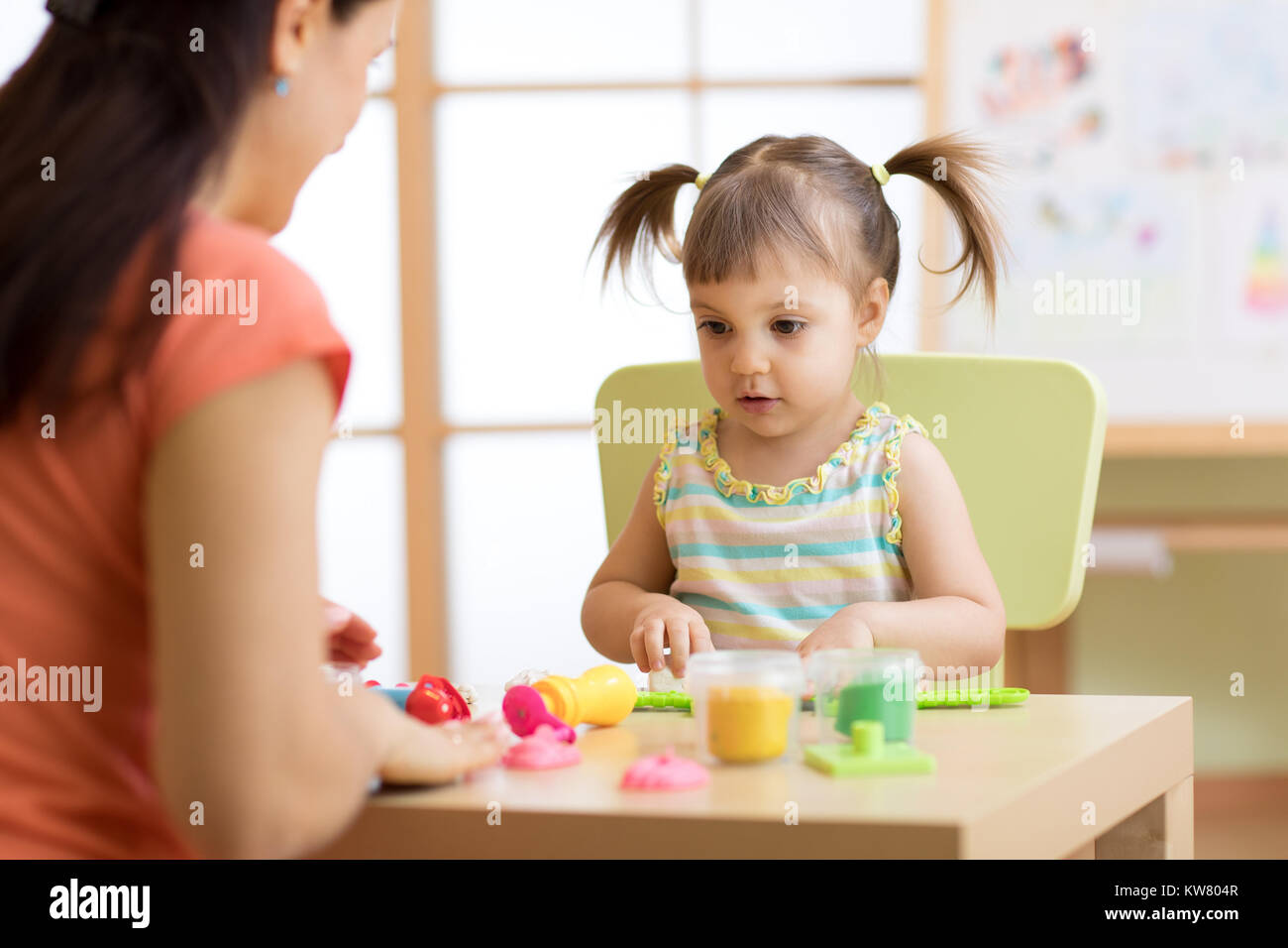 Kind Mädchen und Mutter spielen bunt Ton Spielzeug im Kindergarten oder in den Kindergarten Stockfoto