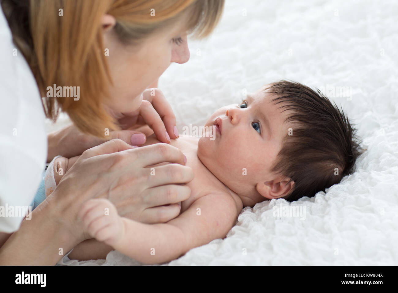 Glückliche Mutter betrachten Baby im Schlafzimmer Stockfoto