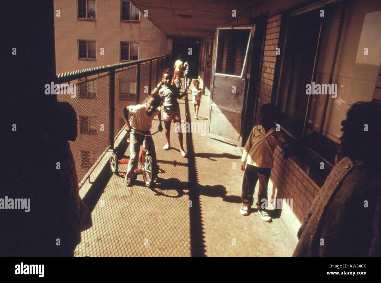 Schwarze Bewohner auf einem der Balkone des Robert Taylor Häuser, ein niedriges Einkommen hochhaus Apartment; Kinder sind Reiten Fahrräder und Spielen auf dem Balkon, Chicago, Illinois, 1973. Bild mit freundlicher Genehmigung von John White/US National Archives. Mit freundlicher Genehmigung der nationalen Archive. Stockfoto