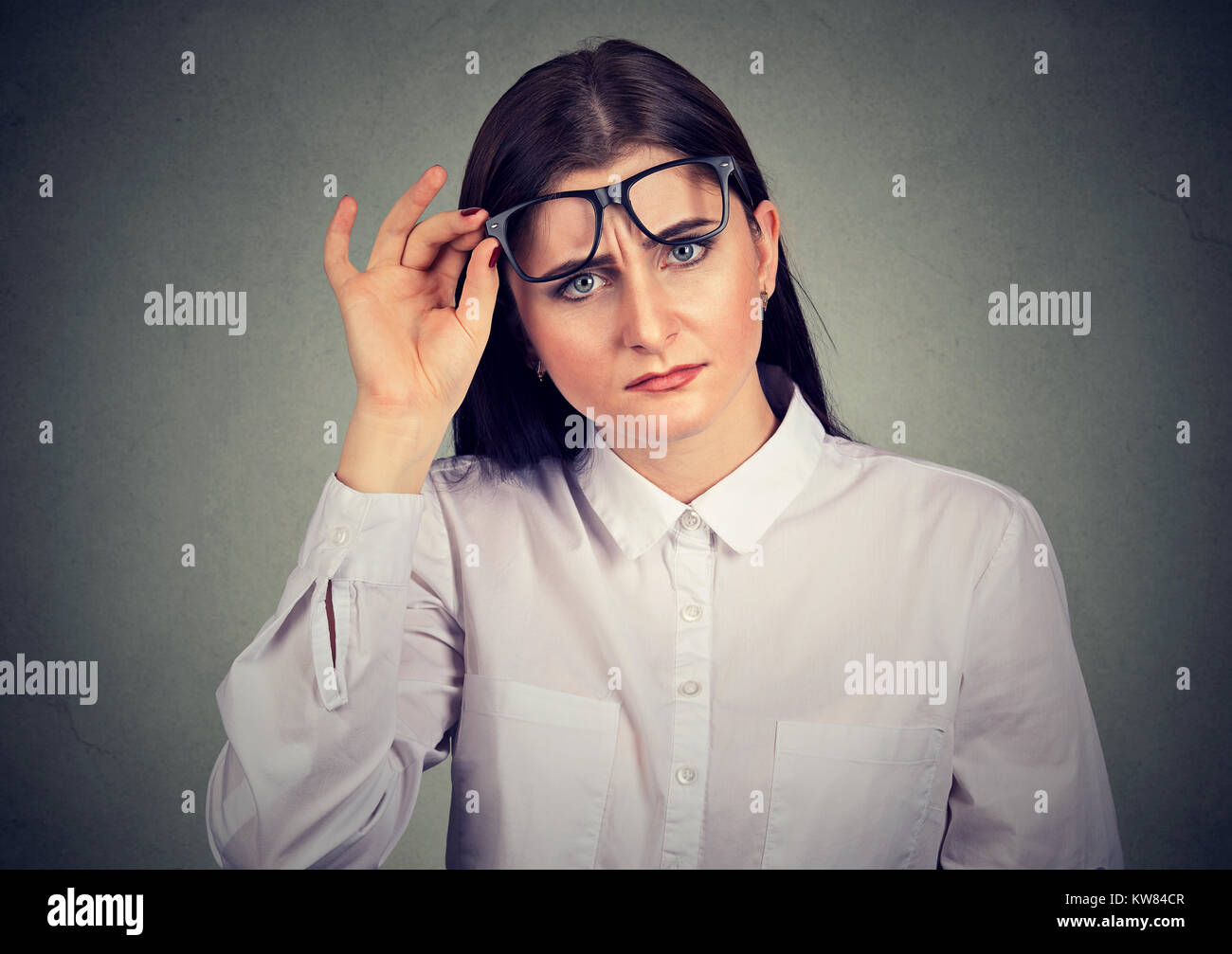 Junge Frau heben Brillen bei Kamera suchen mit Überraschung. Stockfoto