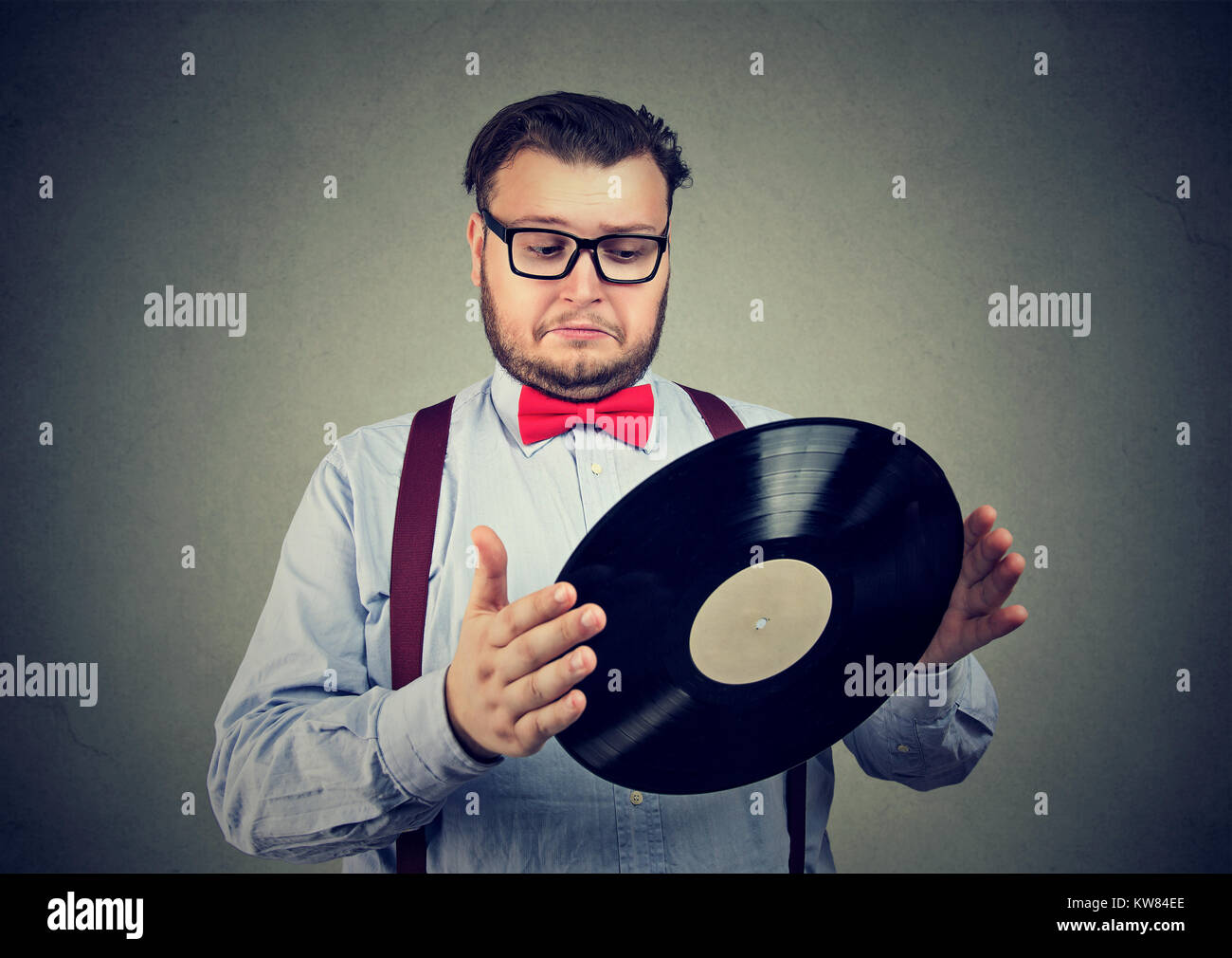 Chunky Mann in formalen Outfit Holding alte Schallplatte verwirrt. Stockfoto