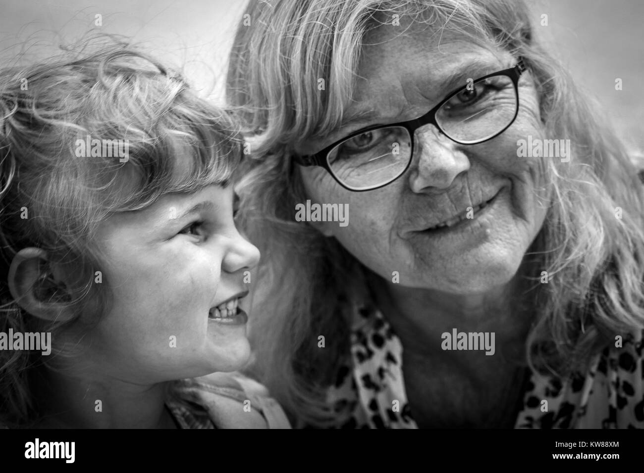 Junge Mädchen schaut zu ihrer Großmutter mit reinem Glück in einer Schwarz-Weiß-Fotografie. Oft haben wir über die Bedeutung der Familie vergessen. Stockfoto