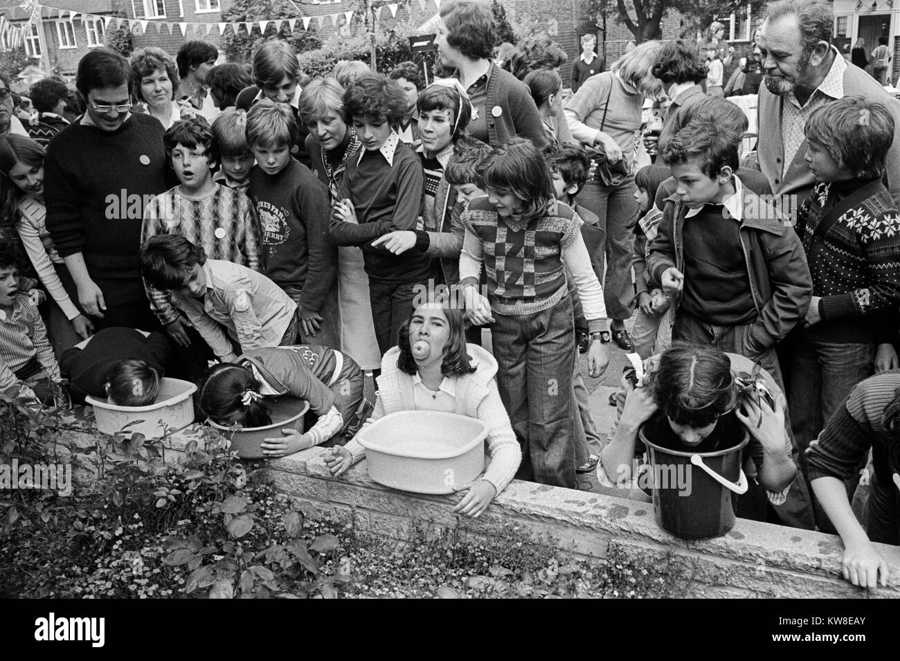 Kinder, die in einem Apple Dunking oder Apple Bobbing oder Bobbing um Äpfel spielen. Silver Jubilee Street Party 1977 Hampstead Garden Vorort. 1970S GB HOMER SYKES Stockfoto