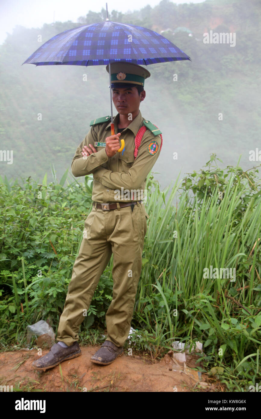Officer unter umbrell auf dem Weg in die Berge, Laos Stockfoto