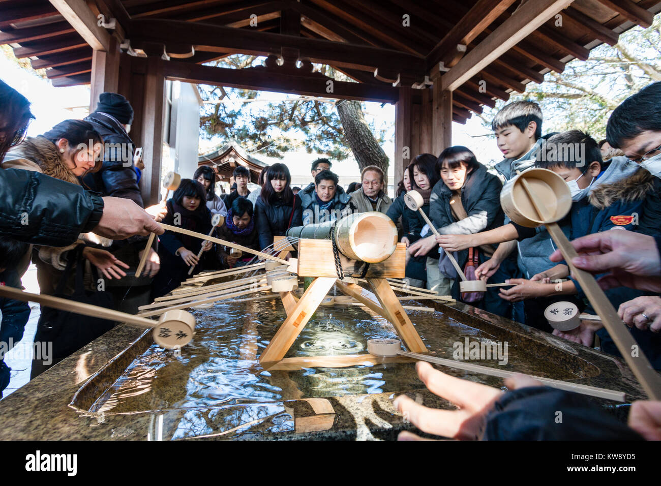 Japan, Nishinomiya. Tag des Neuen Jahres. Menschen um temizuya, Reinigung Becken, mit hölzernen Schöpflöffel, sich vor dem Besuch der Glanz zu reinigen. Sehr voll, voller Menschen. Stockfoto