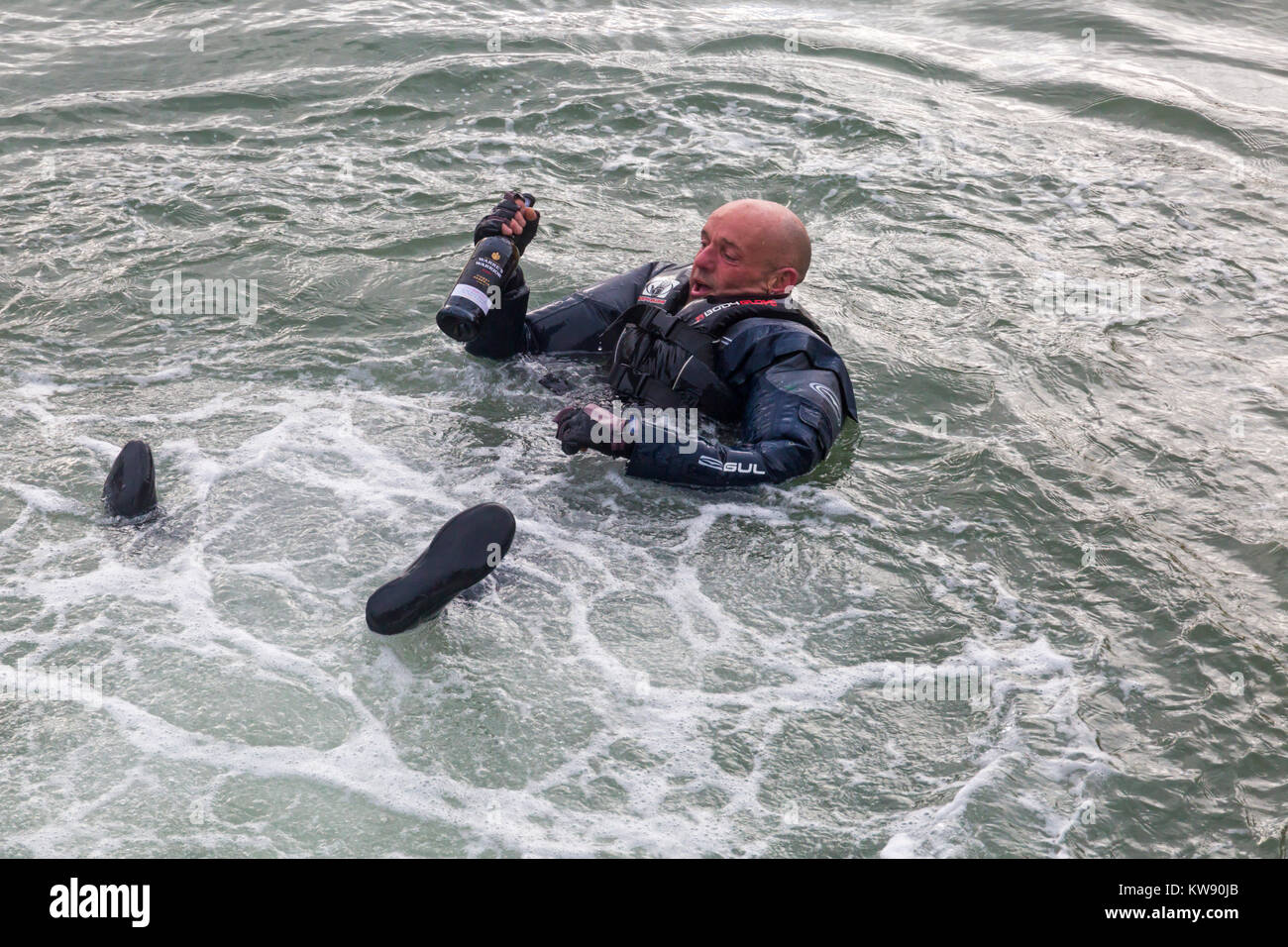 Poole, Dorset, Großbritannien. 1 Jan, 2018. Teilnehmer in Wasser hält eine Flasche Warre's Warrior port Finest Reserve am Neujahrstag Badewanne Rennen in Poole Quay Hafen. Credit: Carolyn Jenkins/Alamy leben Nachrichten Stockfoto