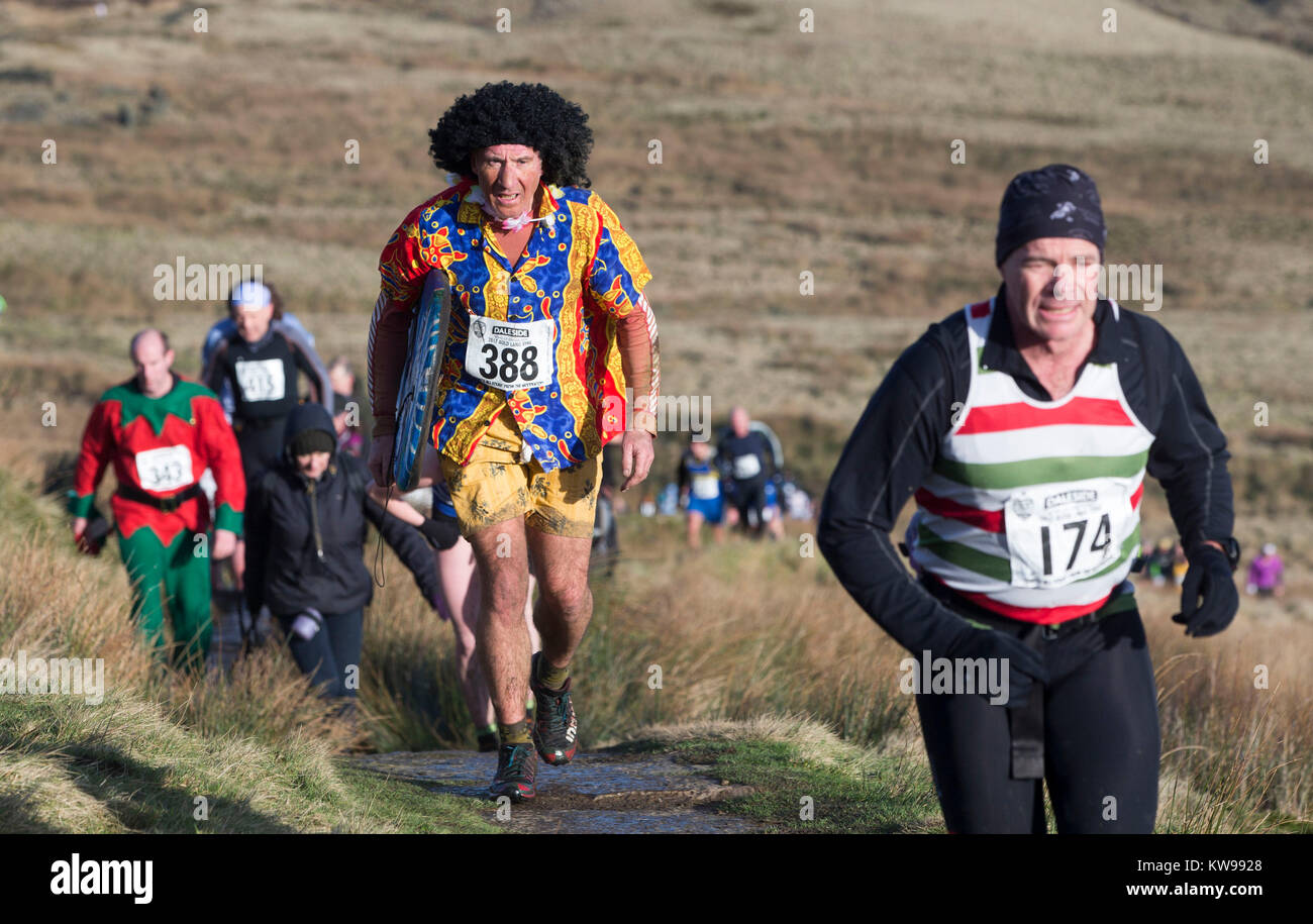 Konkurrenten in Fancy Dress laufen über den Pennine tops in der Nähe von Haworth in der traditionellen Auld Lang Syne fiel Rennen, zieht Hunderte von Läufern, viele in Tracht. Stockfoto