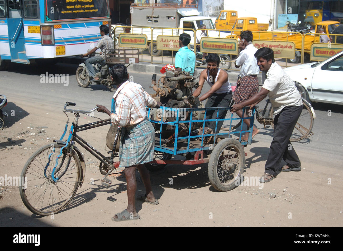 TAMIL NADU, INDIEN, ca. 2009: Männer einen großen Motor in einem dürftigen Fahrradanhänger, etwa in Tirunelveli, Tamil Nadu, Indien 2009. Indiens Wirtschaft relie Stockfoto