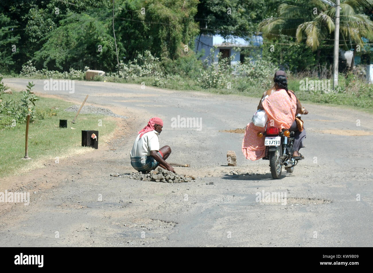 Familie auf Motorrad vermeidet Schlagloch Handwerker in Tamil Nadu, Südindien Stockfoto