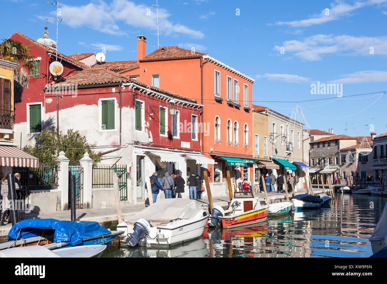 Die Insel Murano, Venedig, Italien, farbenfrohe Gebäude und Geschäfte entlang der Canal Vetrai mit Touristen, Boote und Reflexionen. Stockfoto