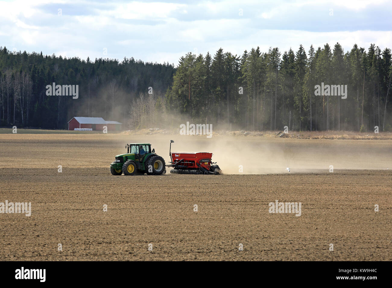 JOKIOINEN, Finnland - 7. Mai 2017: Landschaft der finnischen Landschaft mit John Deere 6830 Traktor und Tume Nova Combi 4000 seeder bei der Arbeit auf dem Feld bei sp Stockfoto