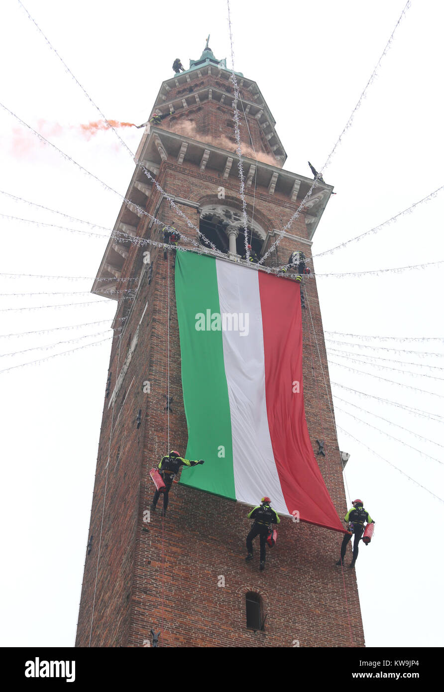 Viele mutige Feuerwehrmann entrollen italienische Flagge auf dem alten Turm "Torre Bissara während einer Festveranstaltung Stockfoto