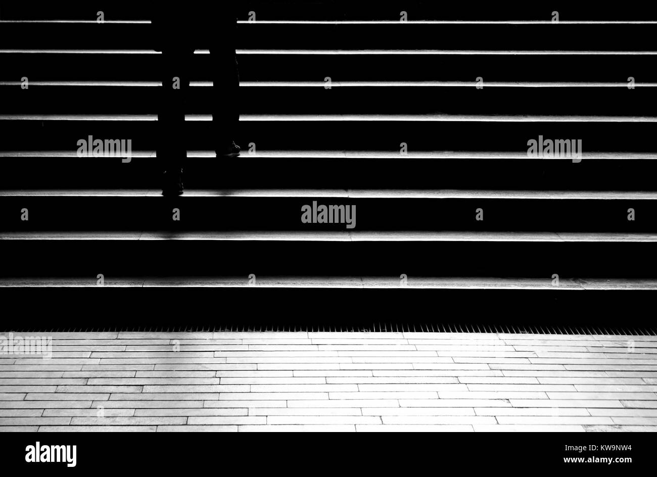 Silhouette Schatten der Person Beine bis zu Fuß zu den öffentlichen Treppen in der Nähe der U-Bahn Passage in der Nacht in Schwarz und Weiß Stockfoto