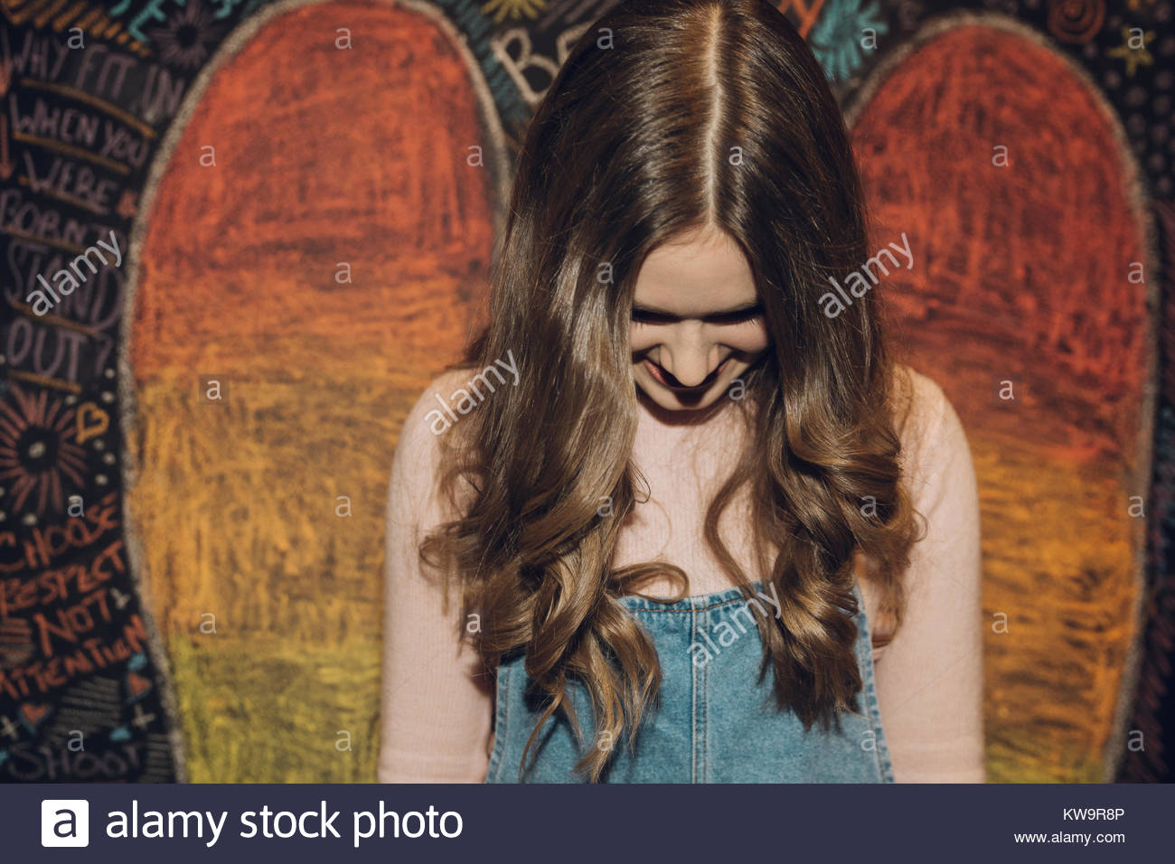 Lächelnd, schüchtern Kaukasischen brunette Tween girl gegen die Wand mit Kreide Flügel Stockfoto