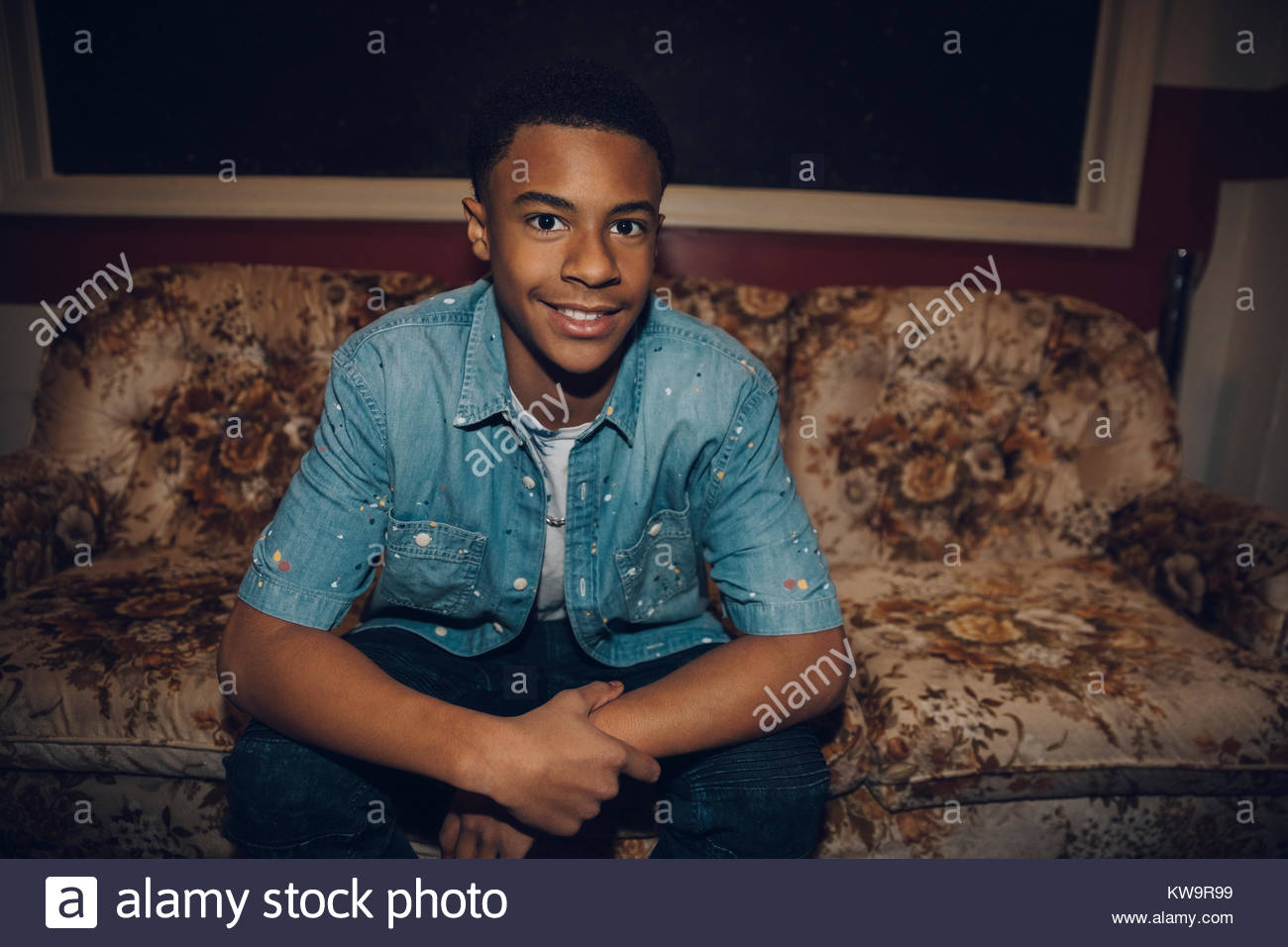 Portrait zuversichtlich African American tween Junge sitzt auf geblümten Sofa Stockfoto