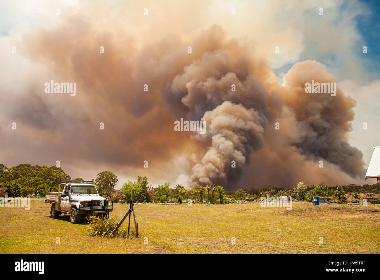 Bushfire auf ländliche Anwesen in New South Wales, Australien. Big smoke, Bäume und Utility Truck Stockfoto