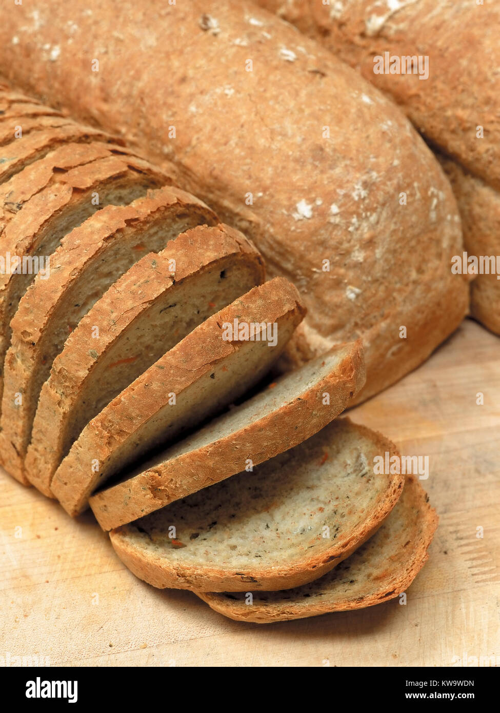 Foto von drei Laibe Brot, ein geschnitten, ruht auf einem Holztisch. Stockfoto