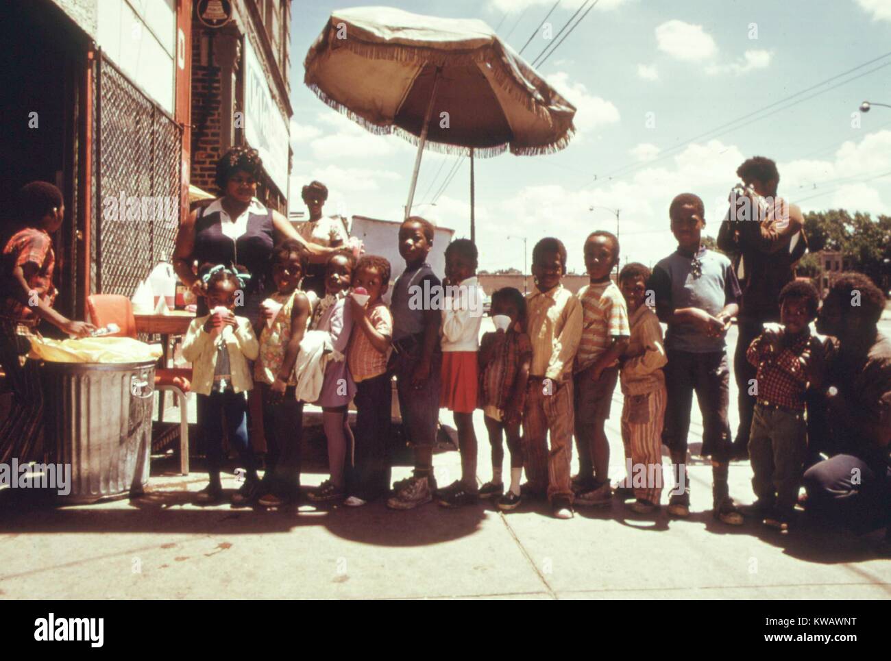 Kinder stehen in der Linie für Schnee Kegel aus einem Bürgersteig auf der Westseite von Chicago, Illinois während der Sommer 1973, 1973. Bild mit freundlicher Genehmigung von John White/US National Archives. Mit freundlicher Genehmigung der nationalen Archive. Stockfoto