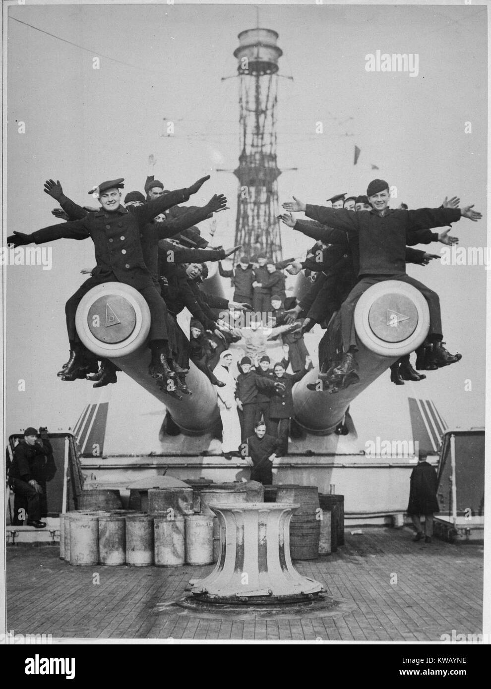 An Bord der USS Texas, vom Krieg in Europa zurück, eine Gruppe von Männern und Frauen, Schwarze oder Weiße Kostüme sitzen auf großen Kanonen und etwas Spaß als "Durchführen der Gobs' mit ausgestreckten Armen und lächelt breit, 1918. Mit freundlicher Genehmigung der nationalen Archive. Stockfoto