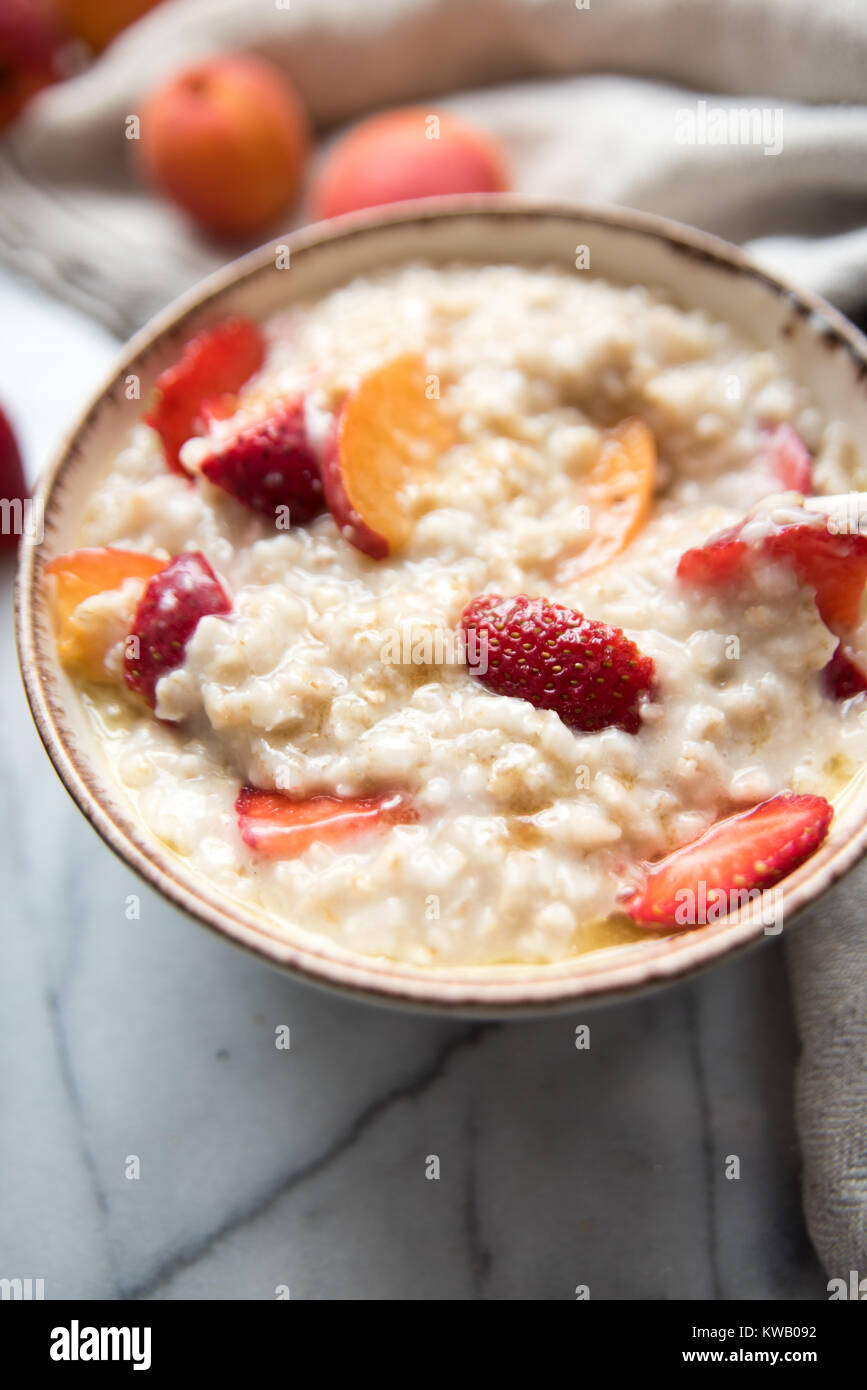 Warmes Müsli Schüssel serviert mit frischen Pfirsichen und Erdbeeren für ein gesundes Frühstück Stockfoto