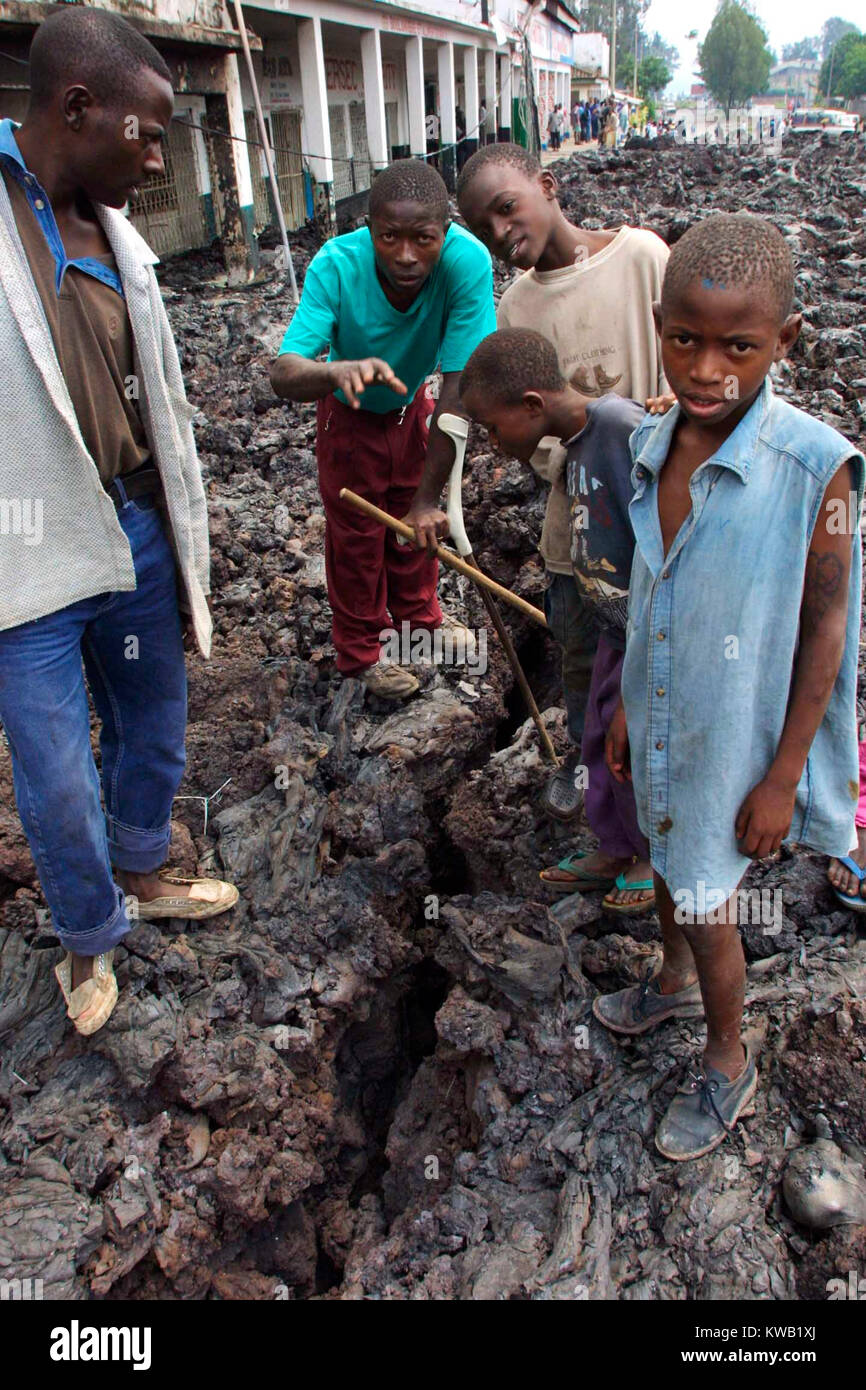 Wenn der Nyriragongo Vulkan auf 18/01/2002 ausbrach, Lava floss in Goma in der Demokratischen Republik Kongo, zerstören ein Drittel der Stadt. Kinder, die über die Kühlung lava schauen die Risse in der Lava auf die glühende Lava unten. Stockfoto