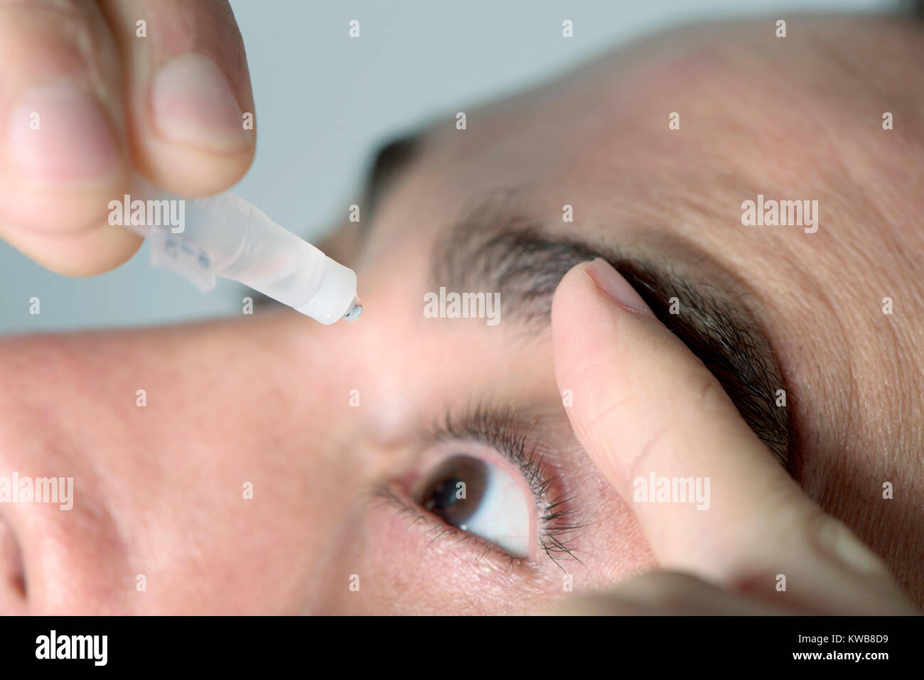 Closuep eines jungen kaukasischen Mann Anwendung der Augentropfen zu seinen Augen Stockfoto