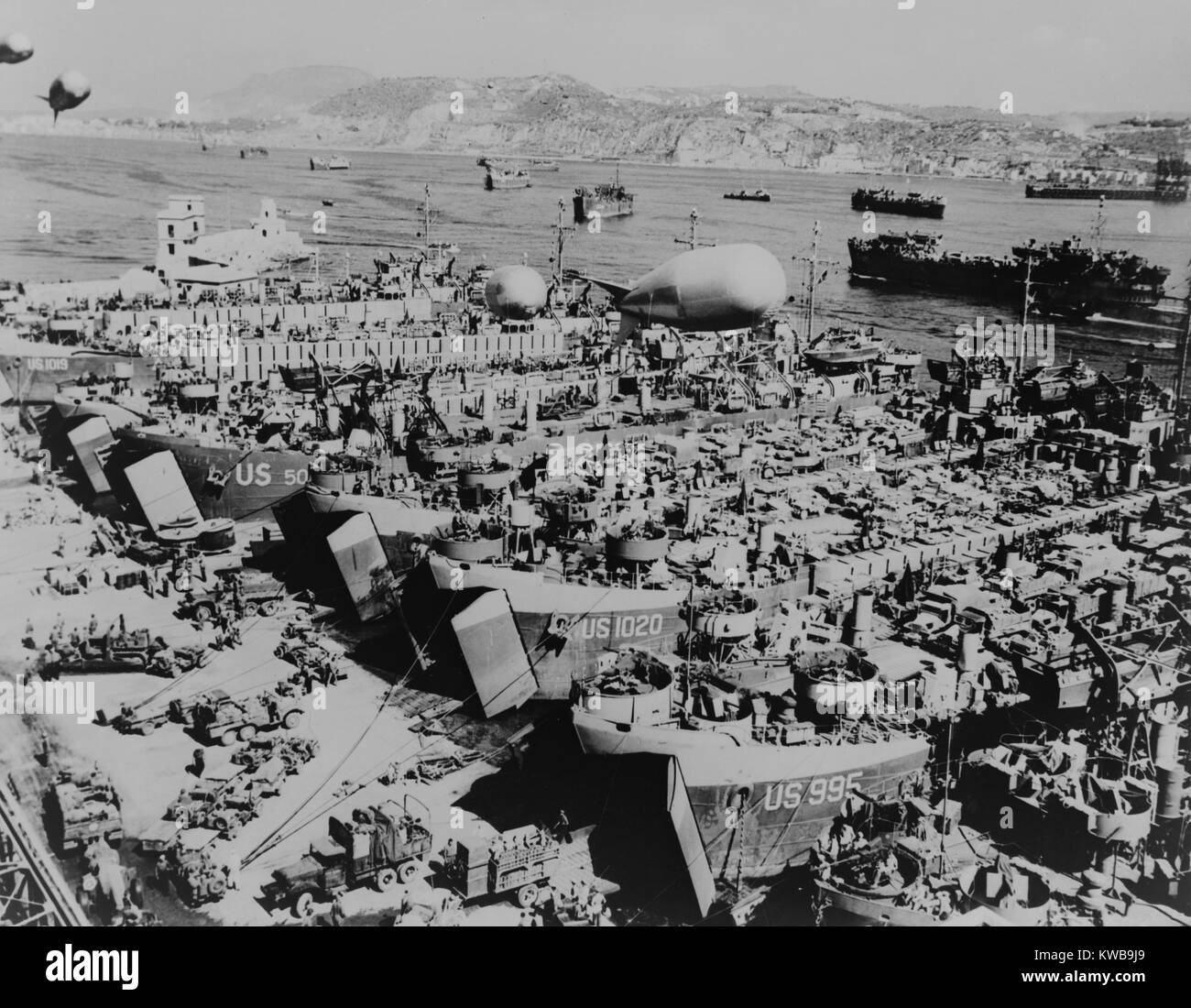 Invasion der Alliierten Schiffe in einem südlichen italienischen Hafen mit Fahrzeugen und Zubehör geladen wird. Sie Angriff an der Südküste Frankreichs, in der Operation Dragoon am 15 August, 1944. Schutzmaßnahmen wie Sperrfeuer Luftballons schweben über dem anchorage. Weltkrieg 2. (BSLOC 2014 10 55) Stockfoto