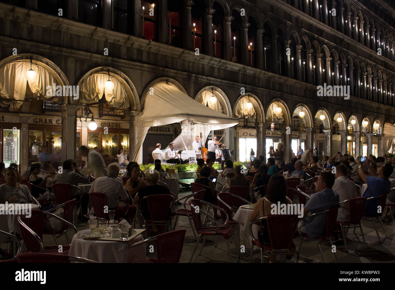 Nacht Blick auf Menschen hören von Musikern in verschwommene Bewegung der klassischen Musik in einer berühmten Restaurant (Quadri) von Saint Mark Square (Piazza San Stockfoto