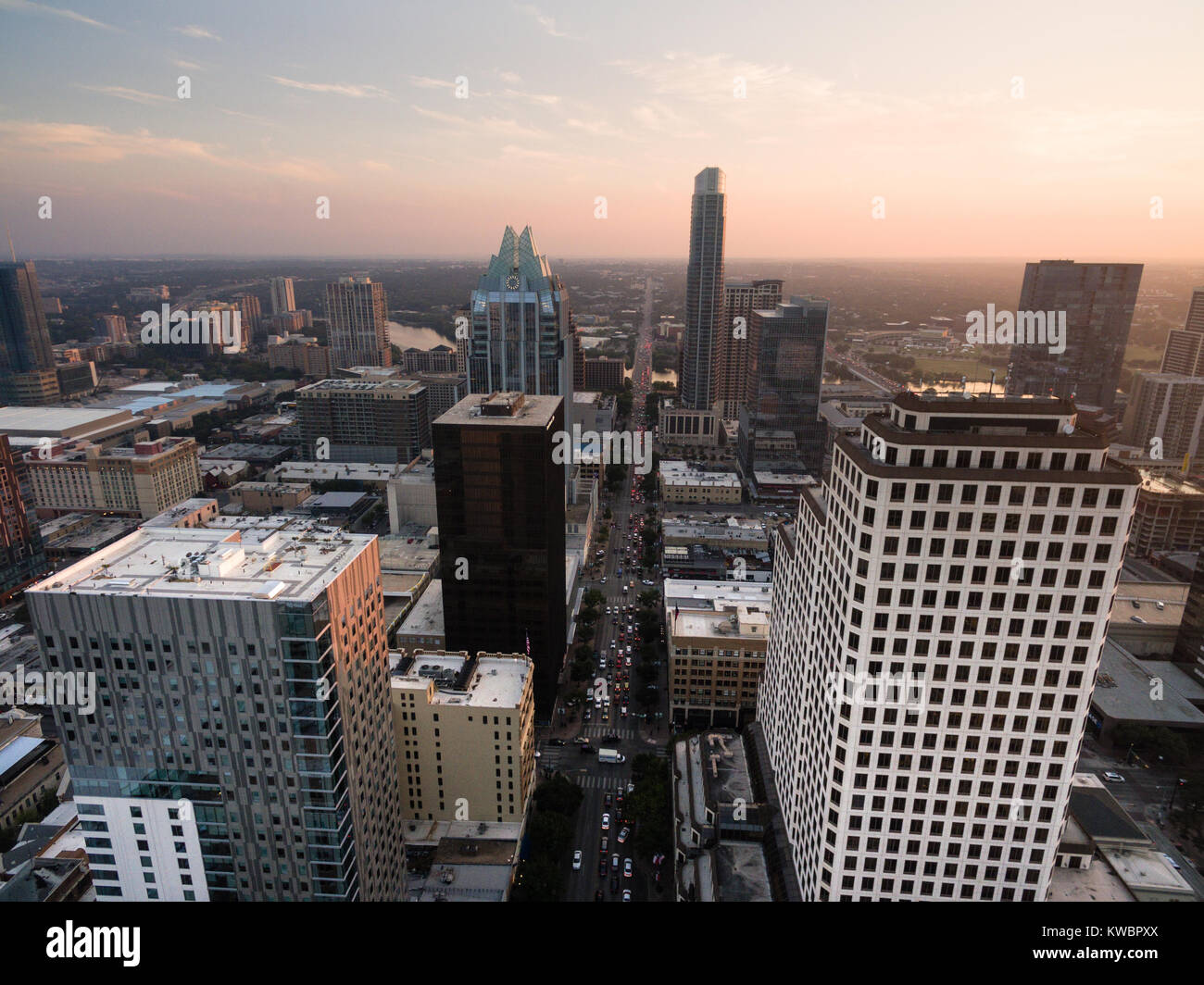 Die Menschen verlassen die Innenstadt von Austin, als die Sonne den Horizont durch ein Labyrinth von hohen Gebäuden Stockfoto
