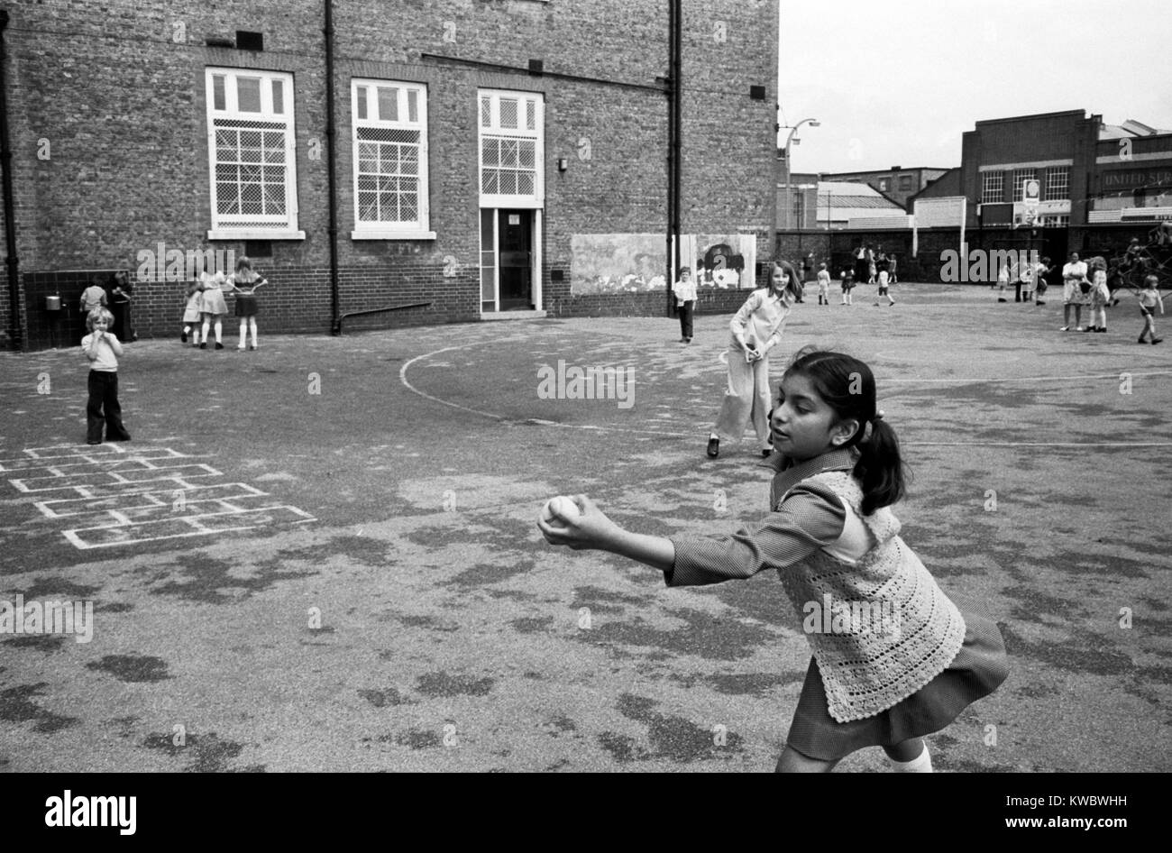 Asiatische muslimischen Mädchen 1970 s, primäre Junior Schule Spielplatz neue Einwanderer spielen fangen einen Ball multiethnischen London 70 s UK HOMER SYKES Stockfoto