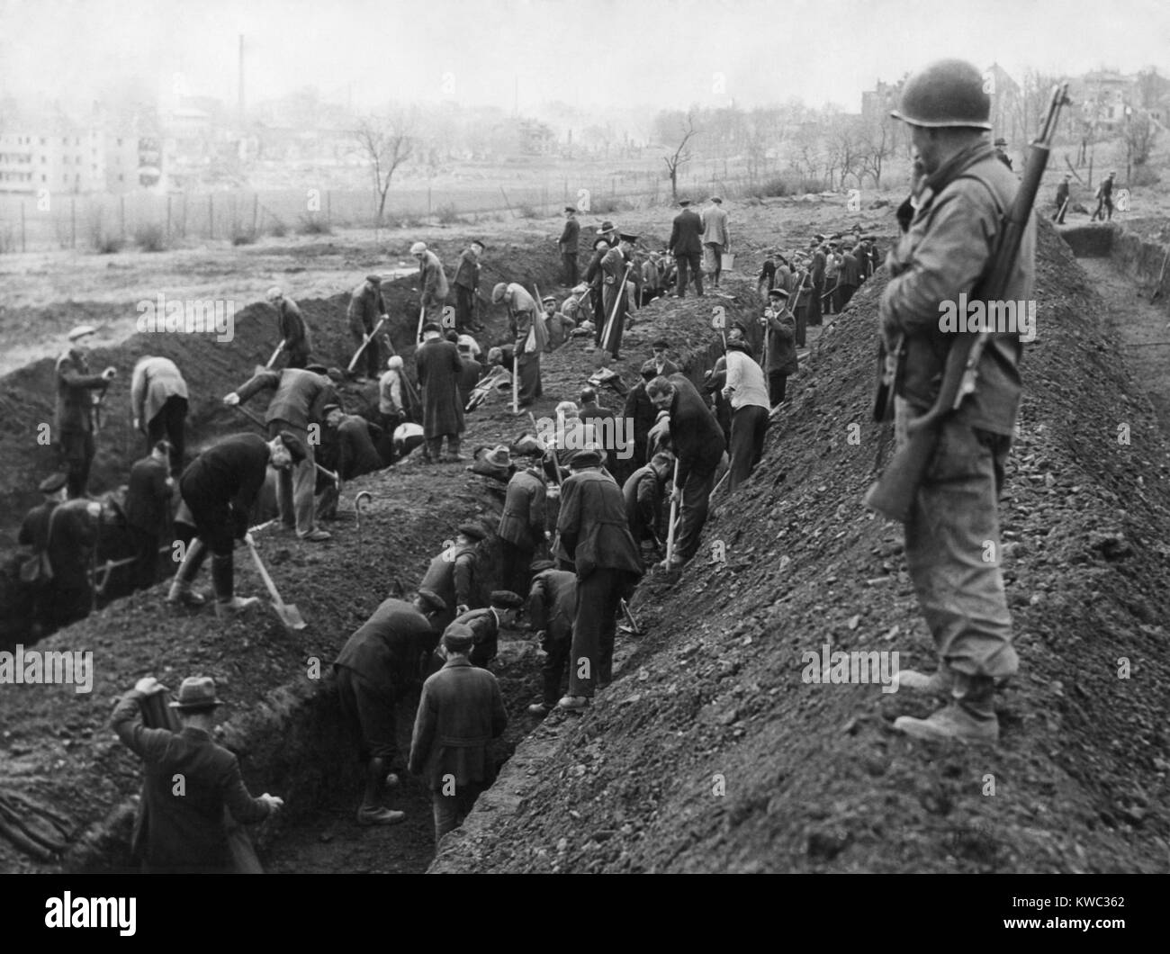 Us-Soldat bewacht das Reburial von KZ-Opfern von deutschen Zivilisten. Ca. April-mai 1945. Unbekannter Standort in Deutschland, Weltkrieg 2 (BSLOC 2015 13 23) Stockfoto