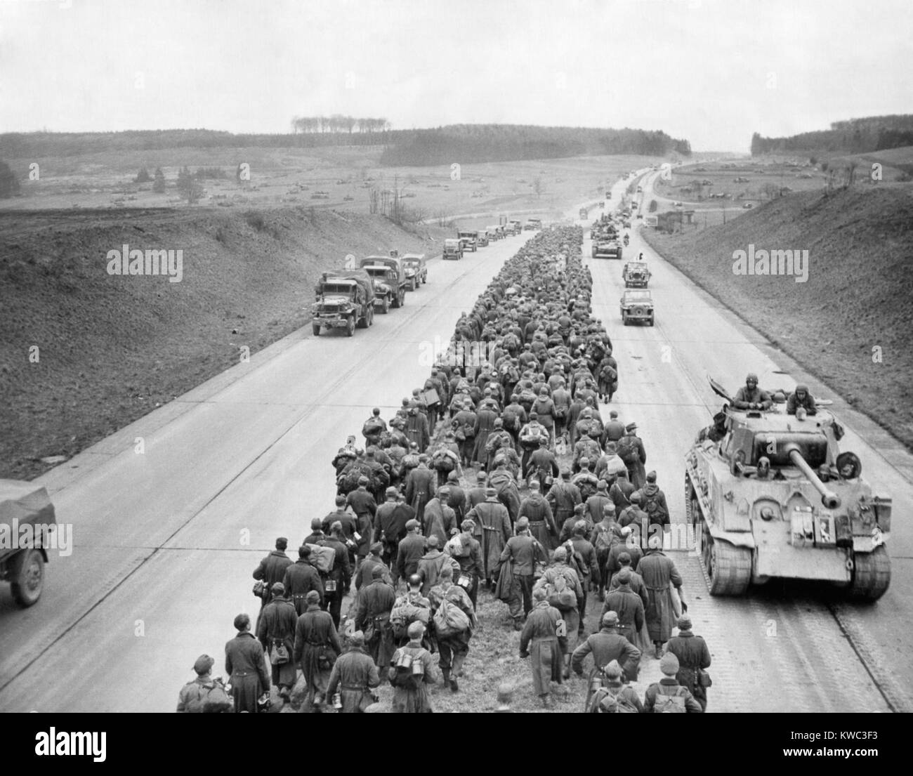Tausende von Deutschen gefangenen März entlang der Autobahn in der Nähe von Giesson, nordwestlich von Frankfurt am Main. In die entgegengesetzte Richtung amerikanische Panzer und Fahrzeuge zum "Battlefront" voraus. Weltkrieg 2, März 29, 1945 (BSLOC 2015 13 75) Stockfoto