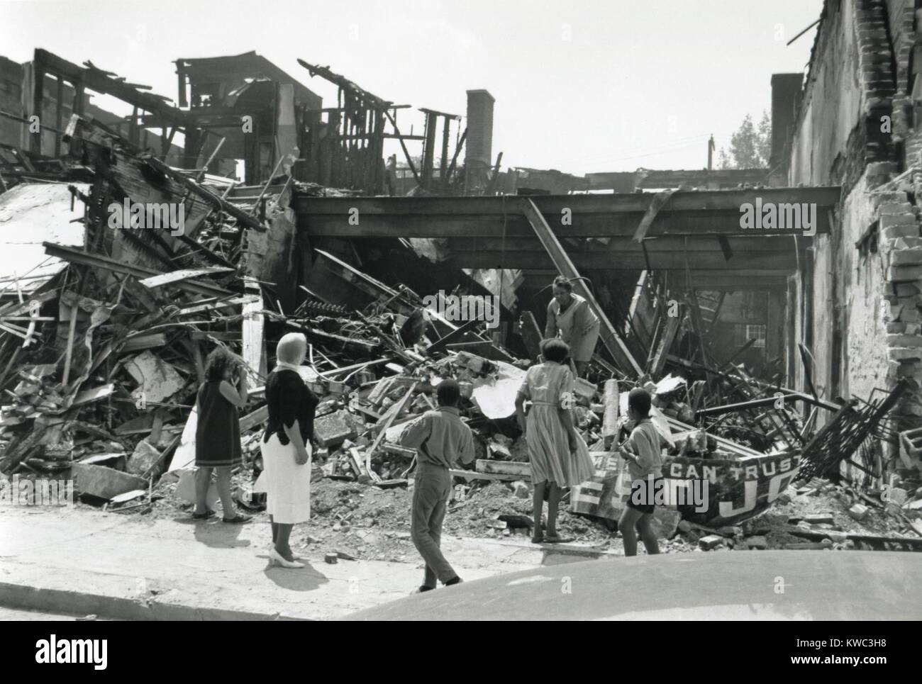 Store zerstört während der Detroit, Michigan, Unruhen vom Juli 1967. Eine afroamerikanische Frau sucht die Ruinen als Fußgänger auf. (BSLOC 2015 14 105) Stockfoto