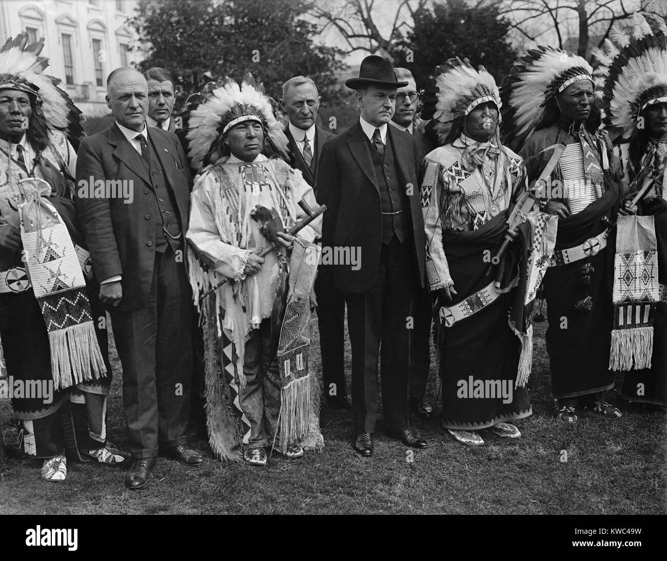 Präsident Calvin Coolidge (Mitte, links) stellt mit kostümierten Native American im Weißen Haus. Ca. 1923-28. Am 2. Juni 1924, Coolidge der Unterzeichnung des Indian Citizenship Act Durchführungsbefugnisse Staatsbürgerschaft auf alle Native American nicht zuvor gewährten Staatsbürgerschaft, obwohl die Ehe weiß, Militärdienst, oder durch besondere Verträge. (BSLOC 2015 15 143) Stockfoto
