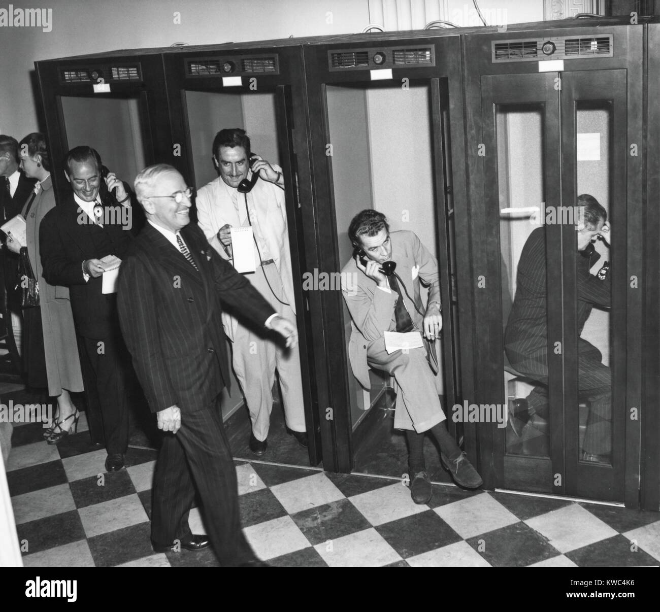 Präsident Harry Truman geht vorbei an Reporter in den Telefonzellen Old State Department Gebäude. Sie sind zurück in ihr Hauptquartier nach Trumans Pressekonferenz, 27. April 1950 berichten. Es war die erste Konferenz zum erfordern Zeitungsmänner sitzen bleiben, entstehen und sich zu identifizieren, wenn Sie Fragen stellen. (BSLOC 2015 2 238) Stockfoto