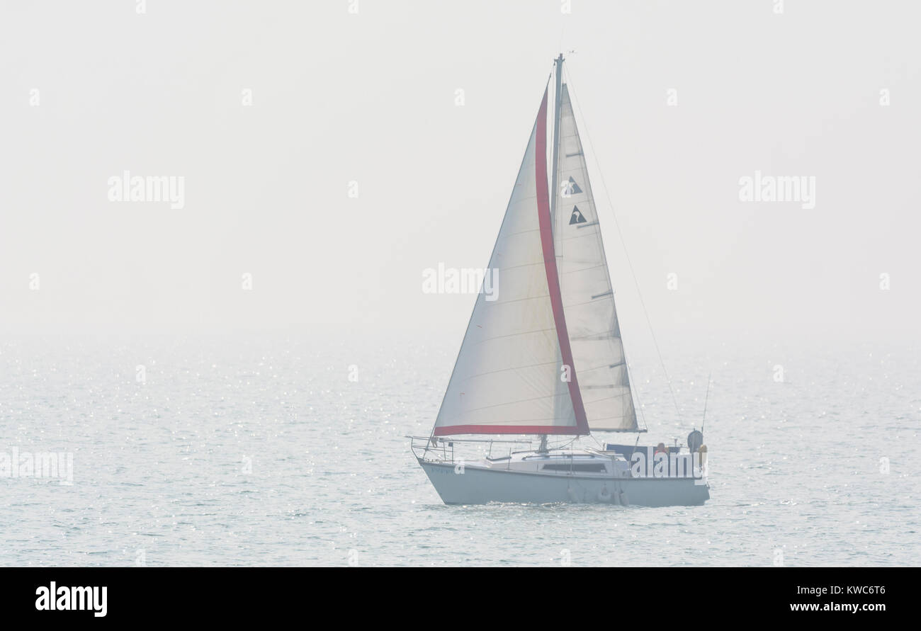Kleine Yacht mit Segeln auf dem Meer in Dunst und Nebel. Stockfoto