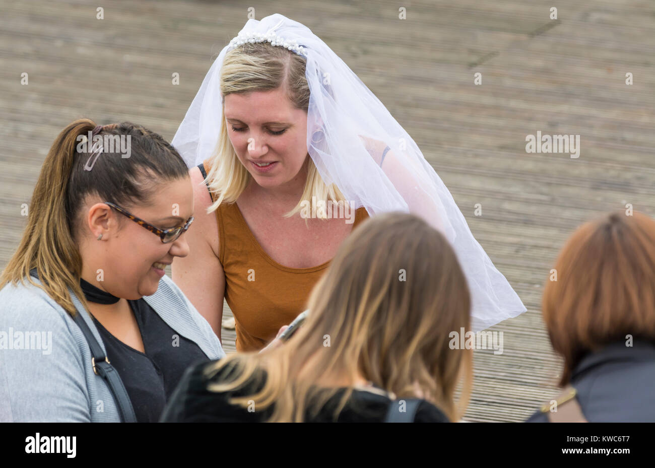 Gruppe von jungen Frauen mit einer Braut zu tragen, eine Hochzeit Schleier auf tagsüber ein Polterabend in Großbritannien. Stockfoto