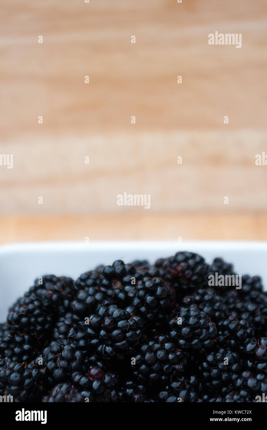 Brombeeren in einer weißen Schüssel mit verschwommenen Hintergrund. Platz für Kopieren. Stockfoto