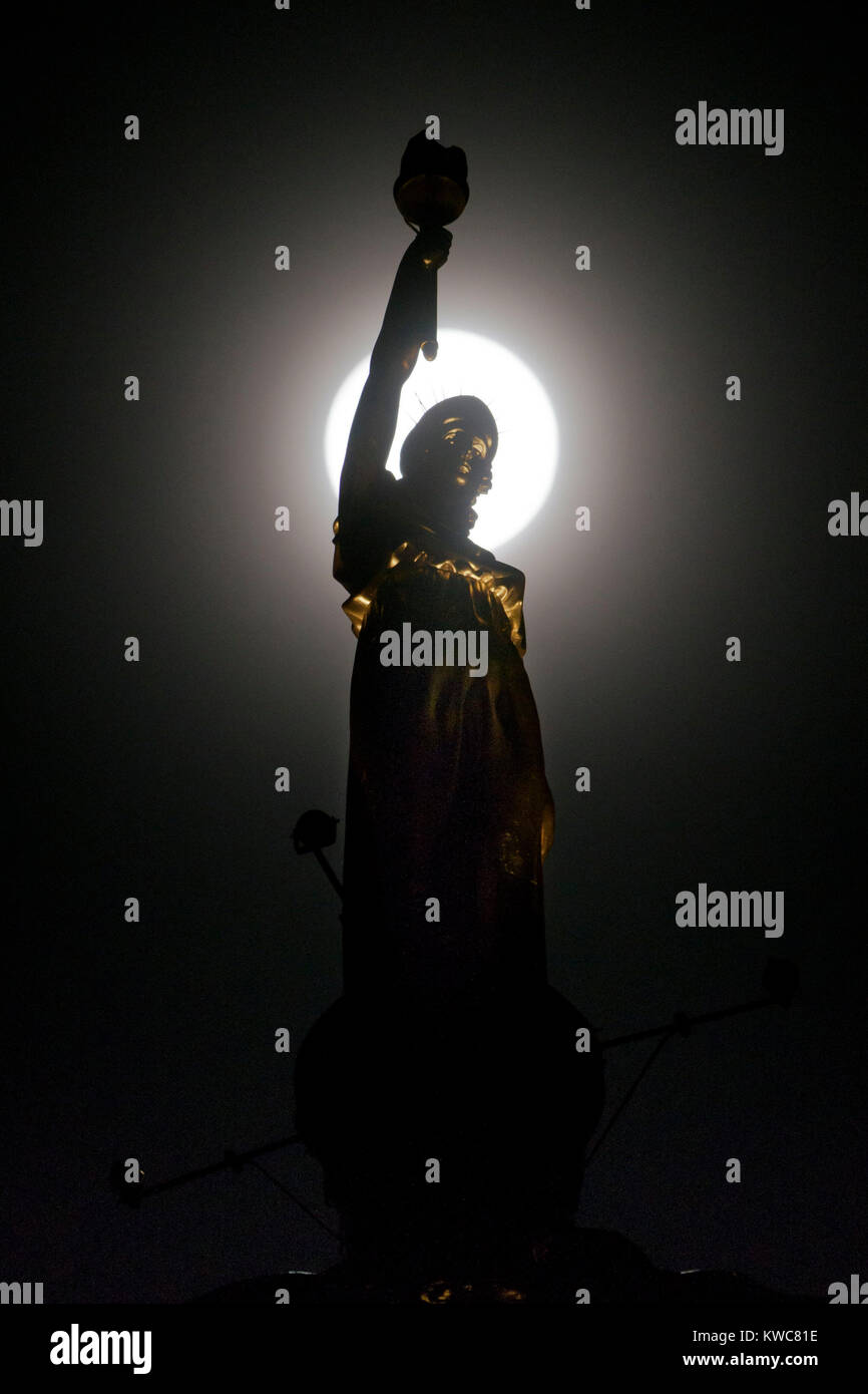 Das neue Jahr supermoon - auch als Wolf Mond - dargestellt in vollen Zügen mitten in der Nacht des 2. Januar hinter Kenny Mackay's Skulptur mit dem Namen "Licht und Leben, die vor kurzem auf der Oberseite des ehemaligen Co-operative Wholesale platziert wurde Gesellschaft Hauptquartier auf der Morrison Street, Glasgow, Schottland bekannt. Stockfoto