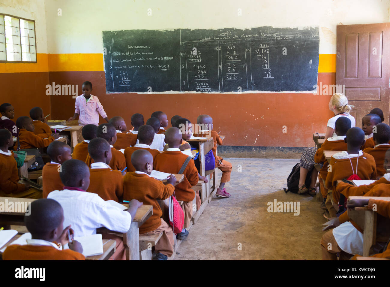 Kinder in Uniformen in der Grundschule Klassenzimmer listetning zu Lehrer in ländlicher Umgebung in der Nähe von Arusha, Tansania, Afrika. Stockfoto