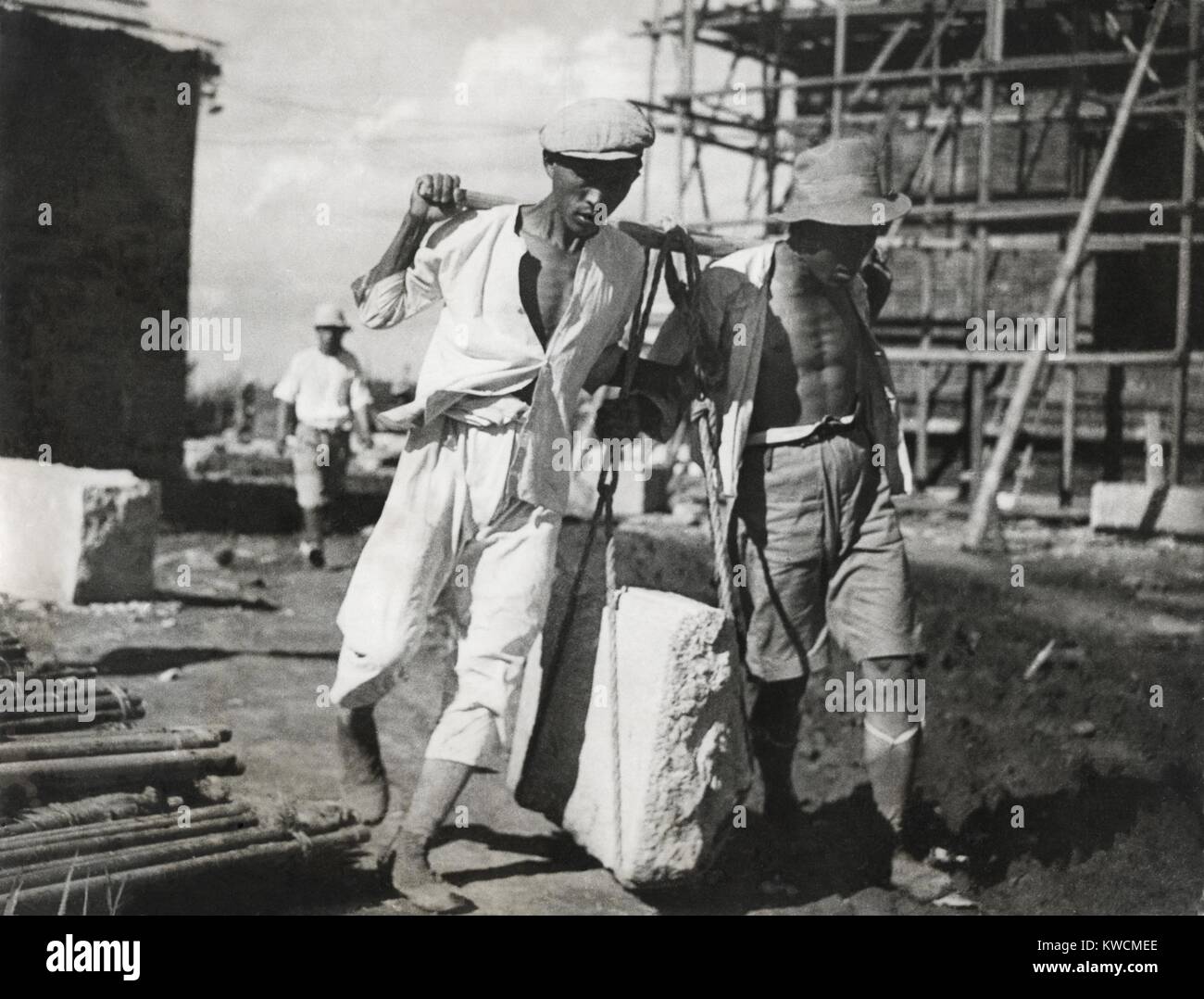 Zwei chinesische Männer arbeiten zusammen, um einen großen Stein auf einer Baustelle leben. Sie verwenden traditionellen vorindustriellen Hebetechniken. Ca. 1930-40 s. - (BSLOC 2014 15 151) Stockfoto