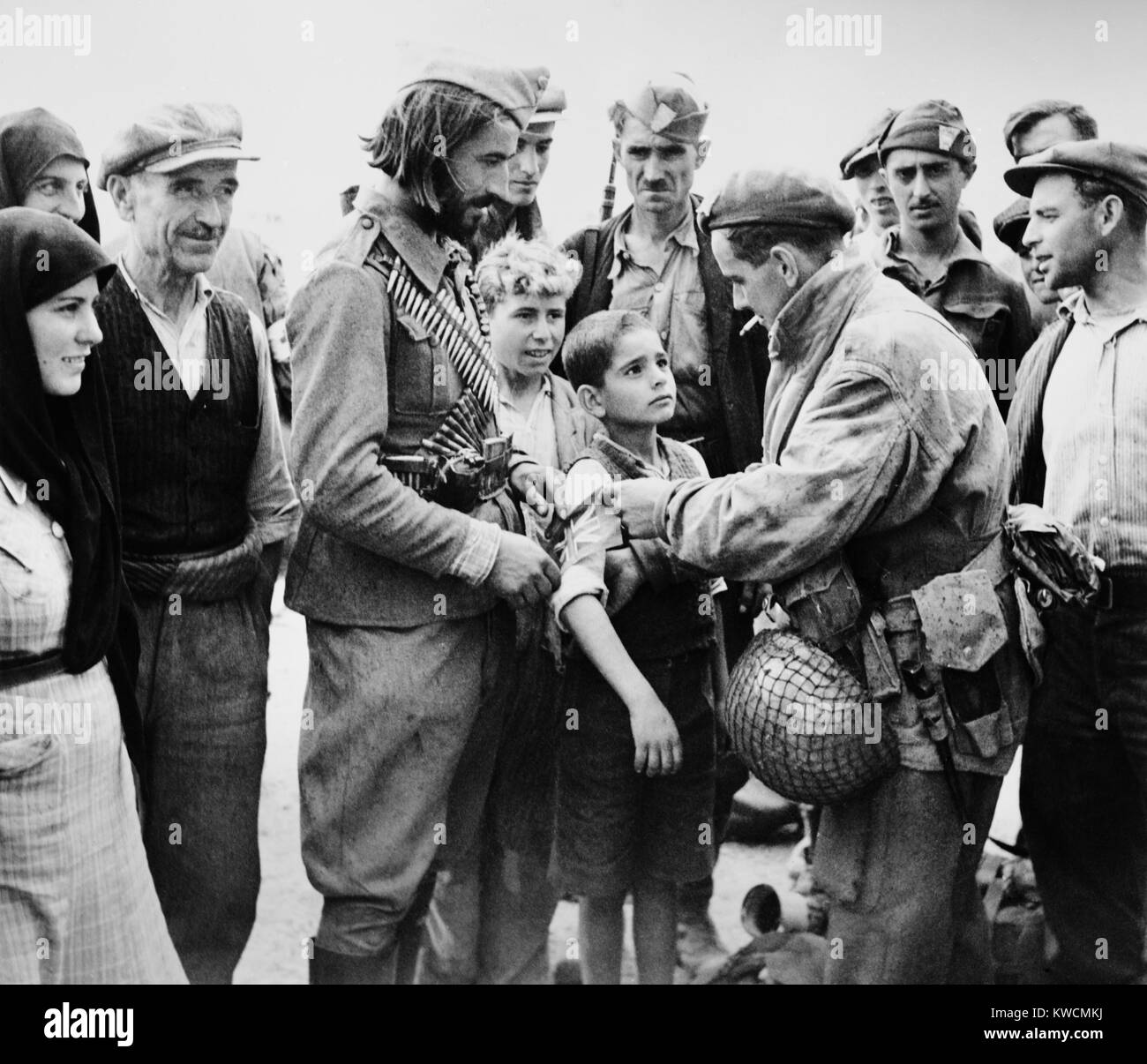 Britischen Befreier des Griechenland, Fixieren eine britische Band am Arm eines kleinen Jungen. Okt. 24, 1944. Die britische Fallschirmspringer aus amerikanischen C-47 über Megara Flugplatz in der Nähe von Athens sprang. - (BSLOC 2014 15 216) Stockfoto