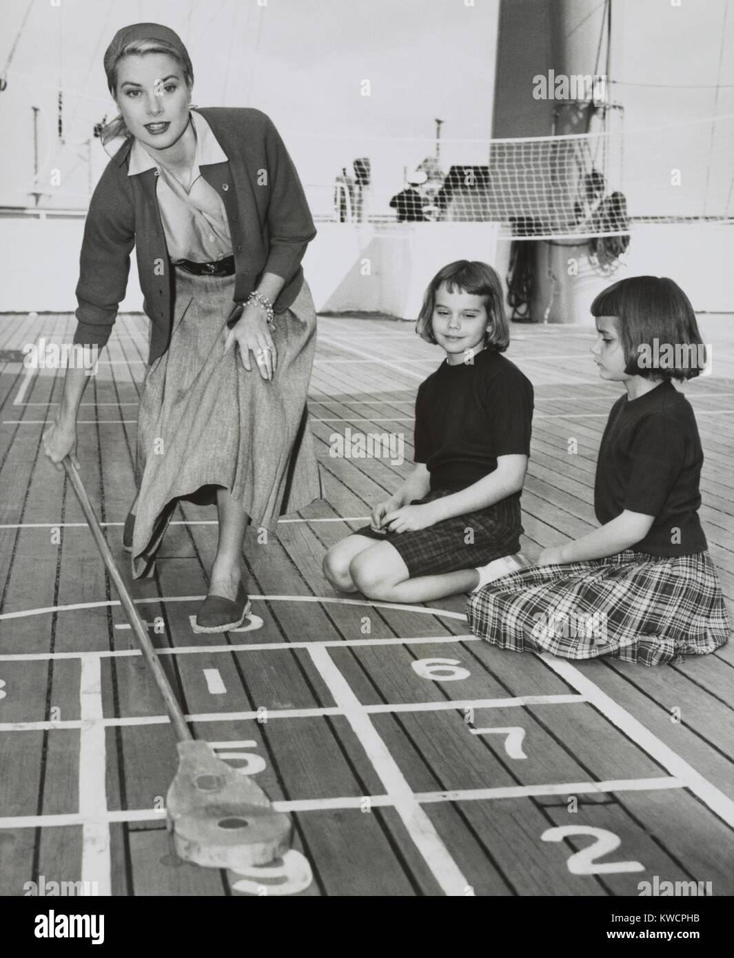 Grace Kelly spielen Shuffleboard auf dem Deck der USS Constitution, 10. April 1956. Das Schiff wurde von Algeciras, Spanien, darauf eingestellt Weg nach Monaco, wo sie mit Fürst Rainier III am 18. April verheiratet. Mit ihr sind ihre Nichten, Margaret und Mary Lee Davis. -(BSLOC 2015 1 19) Stockfoto