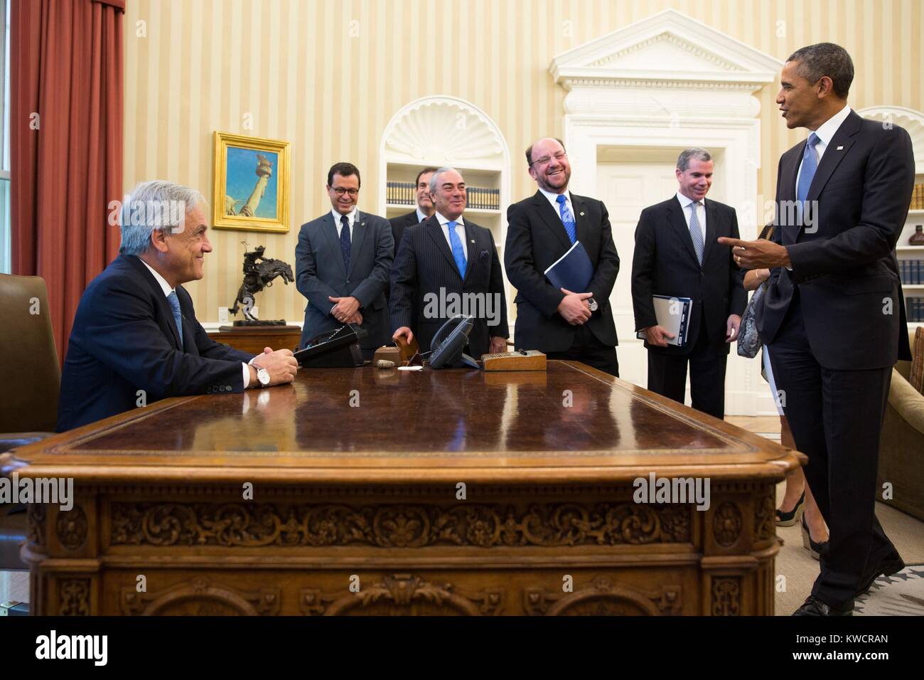 Präsident Sebastian Pinera von Chile sitzt an der Obama-regierung Resolute Desk im Oval Office. Die Chilenische Delegierten teilen die gute Laune. Juni 4, 2013. (BSLOC 2015 3 151) Stockfoto