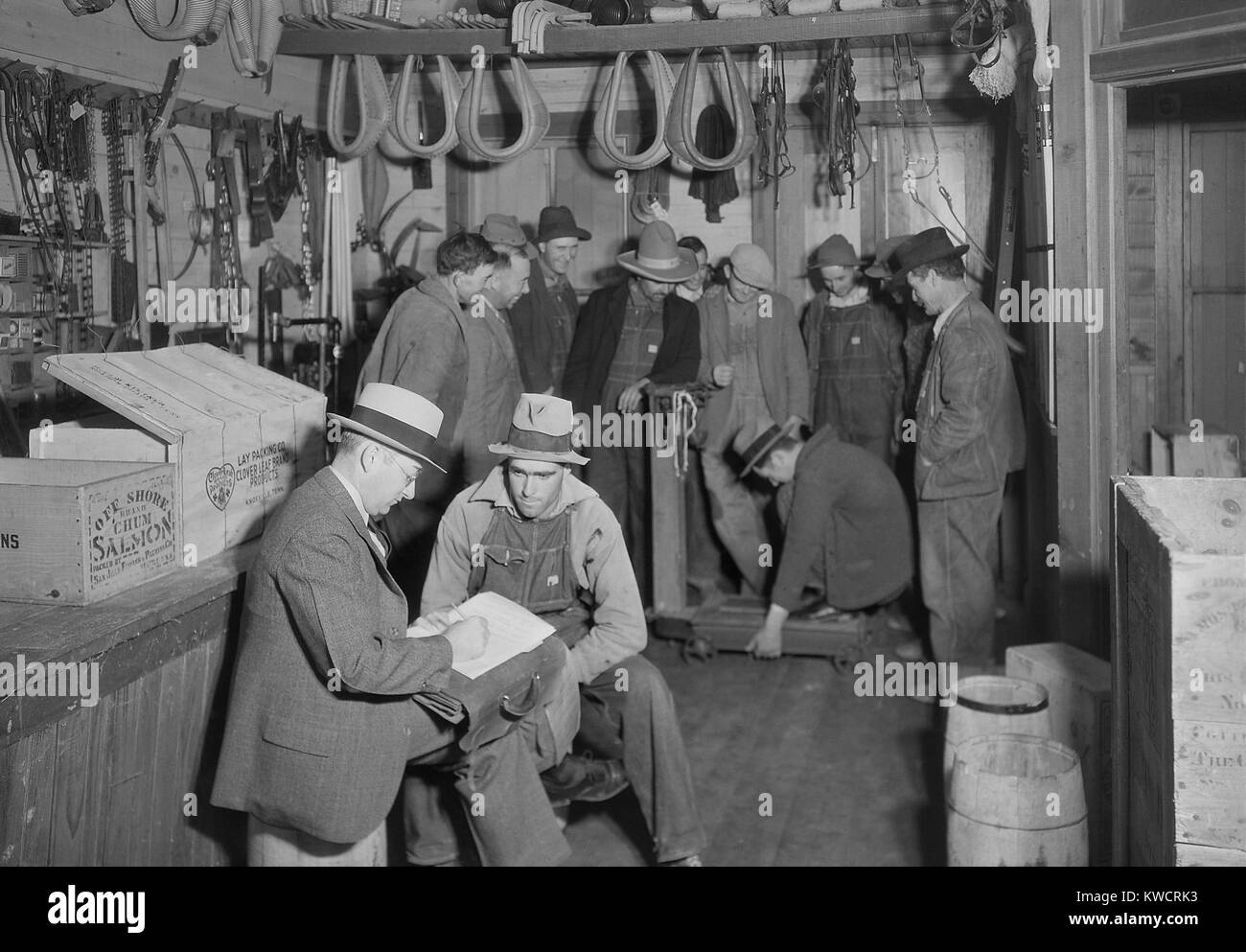 Bewerber für Jobs auf TVA Norris Damm verliefen im Stiner Store, führen Mine Bend, TN. Im Hintergrund amüsieren sich die anderen Bewerber sehen, wer das meiste Gewicht auf die Waage, November 1933 hochziehen kann. Foto von Lewis Hine. -(BSLOC 2015 1 177) Stockfoto