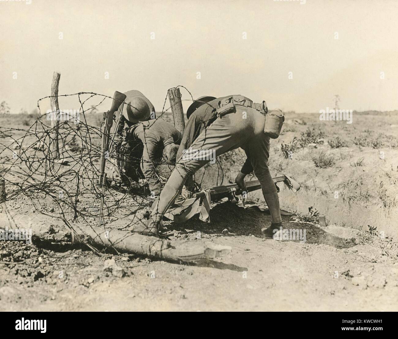 Alliierte Soldaten ein Unfall im Stacheldraht verfangen befreien, während des Ersten Weltkrieges, 1918. Das Gewehr Bajonett stecken in den Boden (von Männer links) war Teil Memorial, und Teil battlefield Signal einen toten Körper zu erholen. Der Soldat auf der rechten hat, was offenbar zur (BSLOC 2017 1 13) Stockfoto