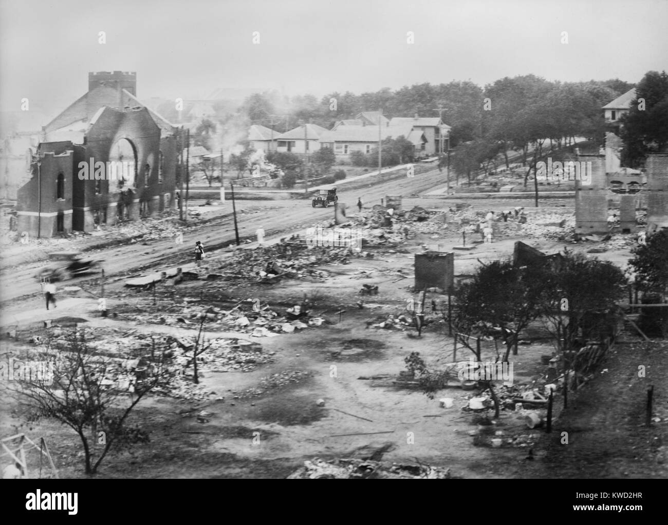 Teil des Distrikts 1917 Tulsa Rassenunruhen verbrannt, einschließlich der Ruinen von Mt. Zion Baptist Church. Drei Menschen gehen durch die Verwüstung (BSLOC 2017 20 80) Stockfoto