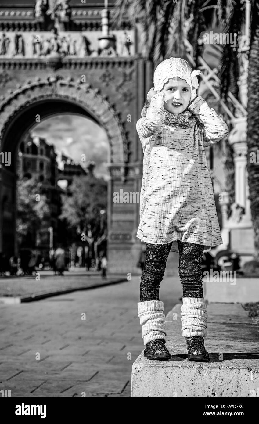 in Barcelona für einen perfekten Winter. In voller Länge Portrait von trendige Mädchen in der Nähe von Arc de Triomf in Barcelona, Spanien halten Sie ihren Hut Stockfoto