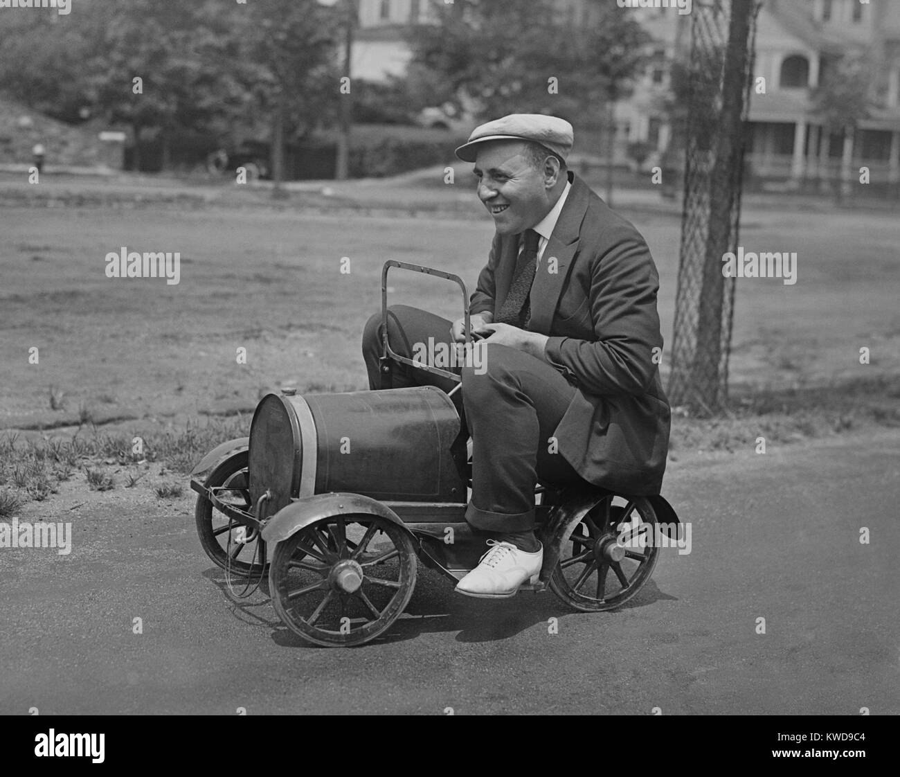 Mann auf Spielzeug des Kindes Auto in einer Straße sitzt. New York City Nähe, 1920er Jahre (BSLOC 2016 10 133) Stockfoto